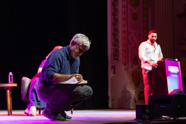 Donald Cohen jotting down something on stage