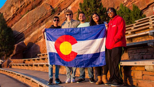 A group of youth hold the flag of Colorado state