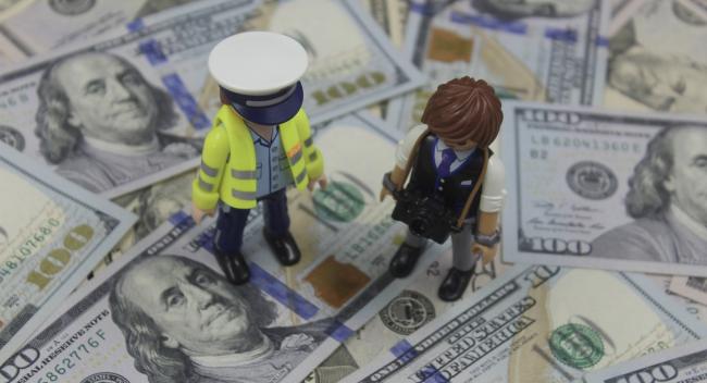 Two LEGO figurines standing on a pile of cash